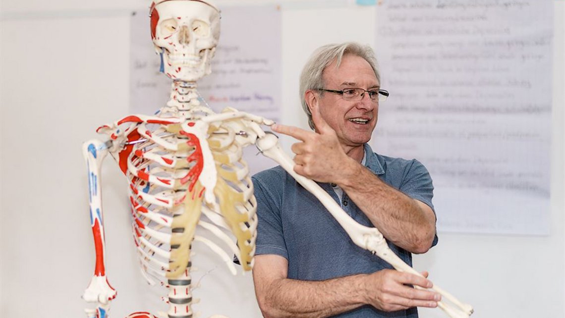 Dozent mit Anatomie-Skelett erklärt Bewegung