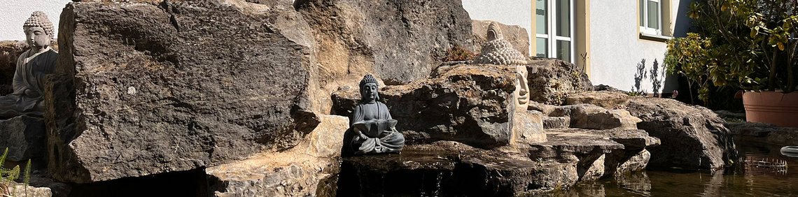 Natursteinbrunnen mit Wasserlauf vor dem Gebäude