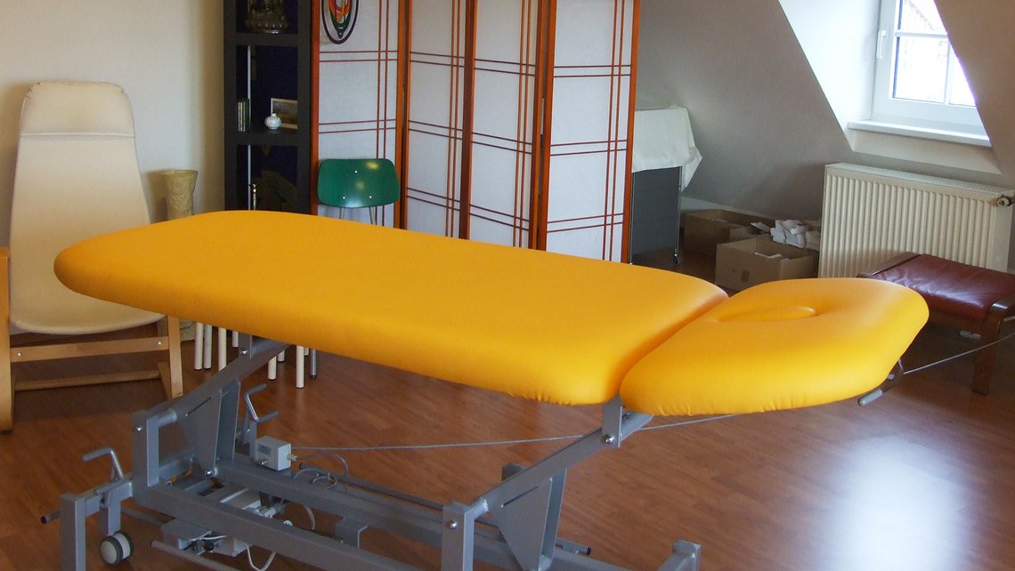 Therapieraum mit gelber Behandlungsliege in der Kybalion Einrichtung