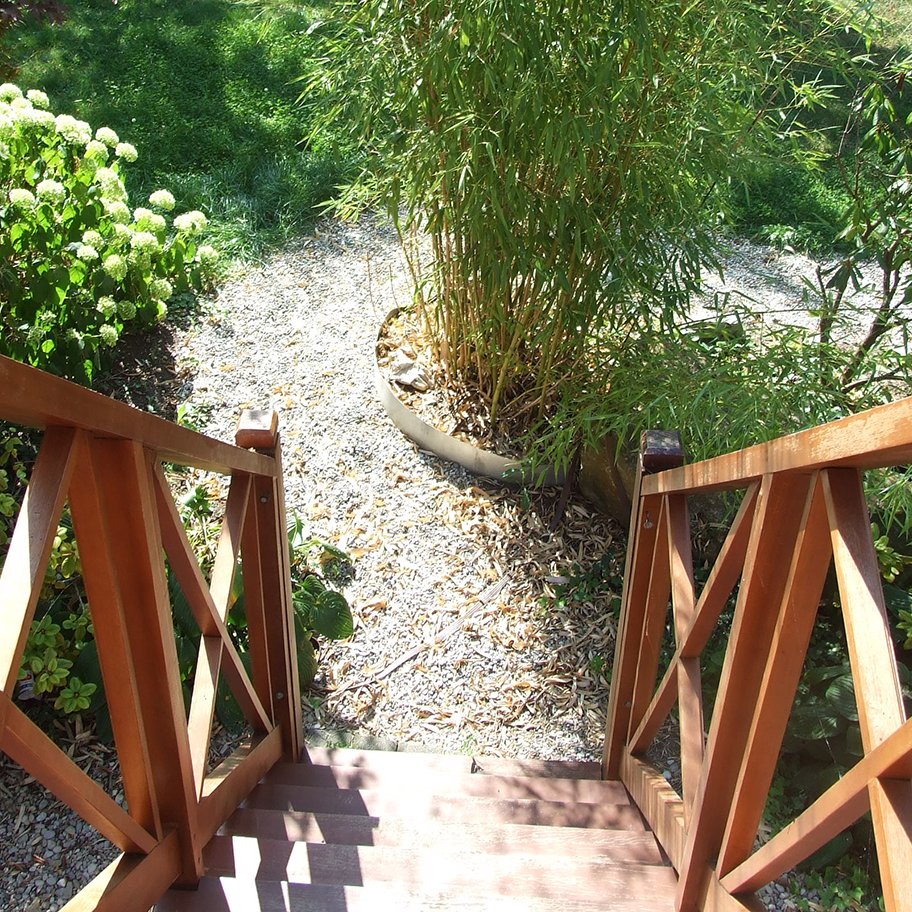 Holzbrücke mit Treppe, die in den Gartenbereich führt