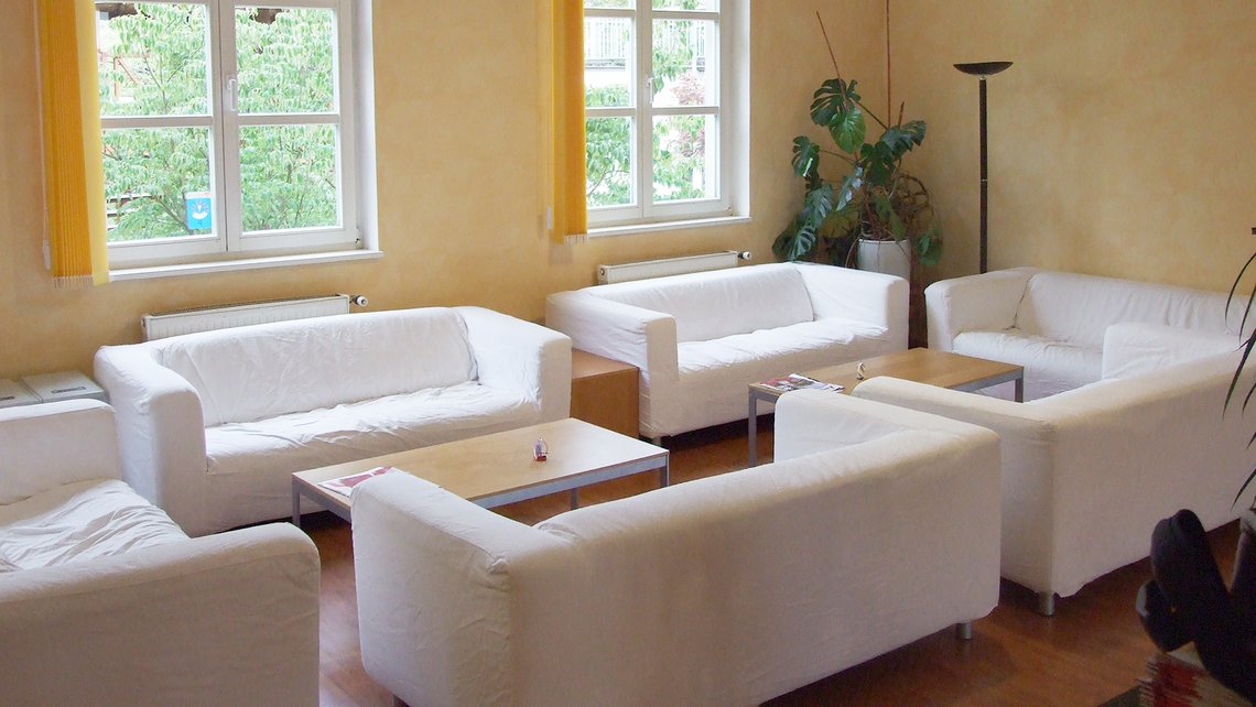 Gemütlicher Innenraum mit weißen Sofas und großen Fenstern in der Kybalion Einrichtung