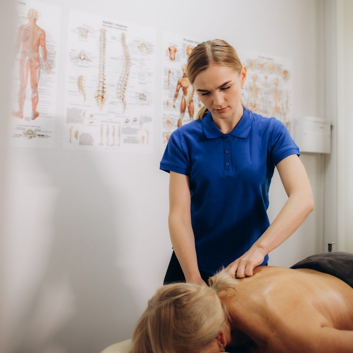 Physiotherapeutin behandelt Patienten auf einer Liege im Praxisraum