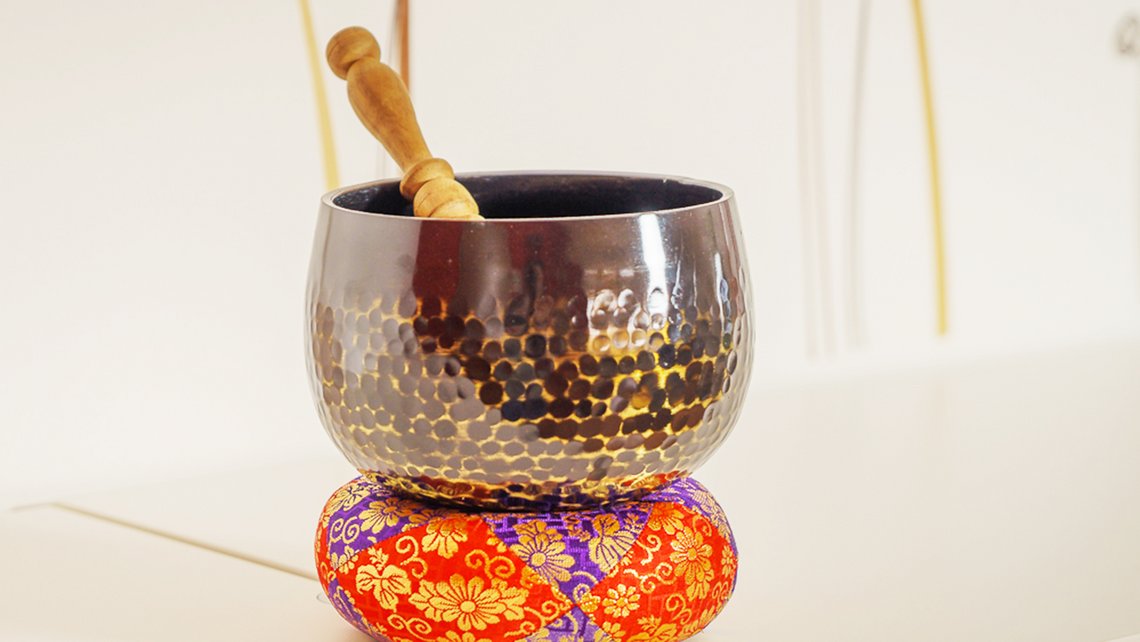 Klangschale mit hellem Hintergrund, mit einem Schlägel