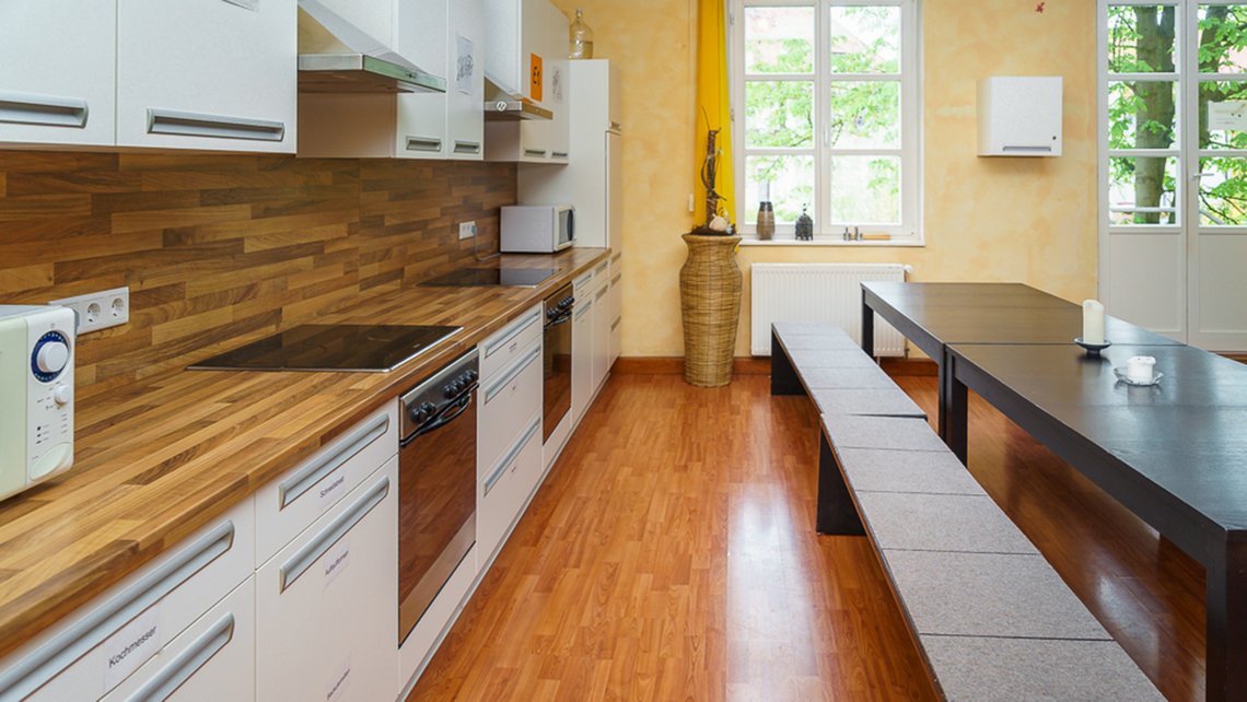 Moderne Küche mit Holzarbeitsplatte und hellen Schränken in der Kybalion Schule