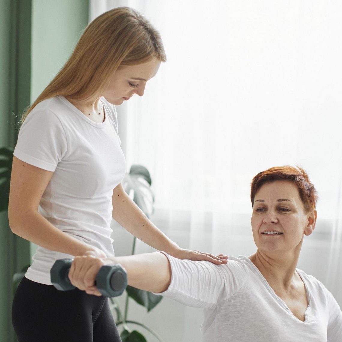 Physiotherapeutin erklärt Behandlungsschritte einem Patienten