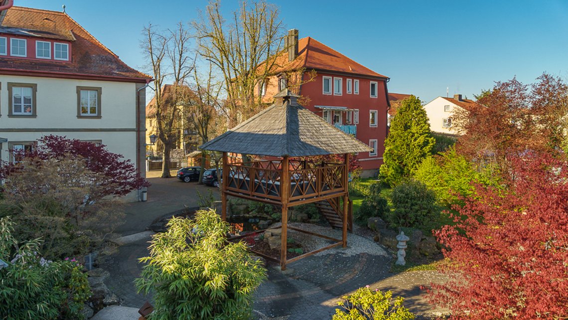Schulgebäude mit bepflanztem Vorhof und Herbstbäumen im Außenbereich