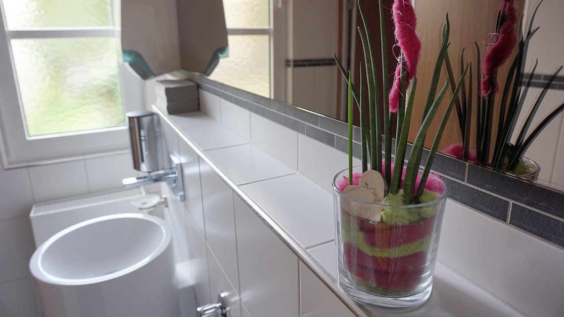 Modernes Waschbecken mit Spiegel und Pflanzen im Kybalion Gebäude