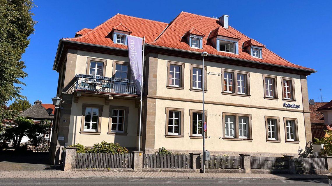 Vorderansicht des Kybalion Schulgebäudes mit rotem Dach und heller Fassade