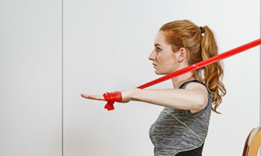 Frau sitz auf einem Stuhl und Trainiert mit einem Fitnessband