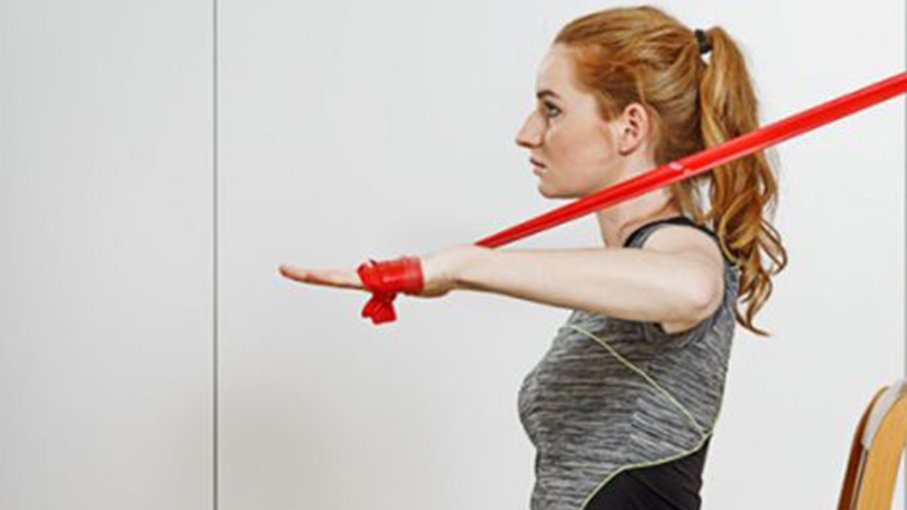 Frau sitz auf einem Stuhl und Trainiert mit einem Fitnessband