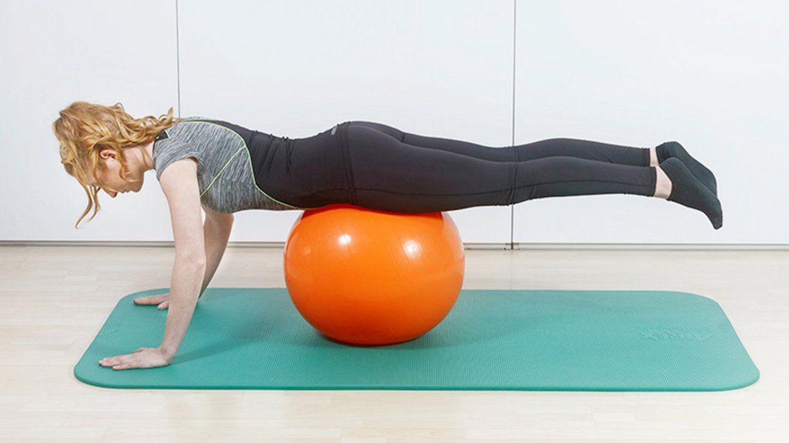 Frau führt Übungen auf einer Matte aus, mit einem Gymnastikball