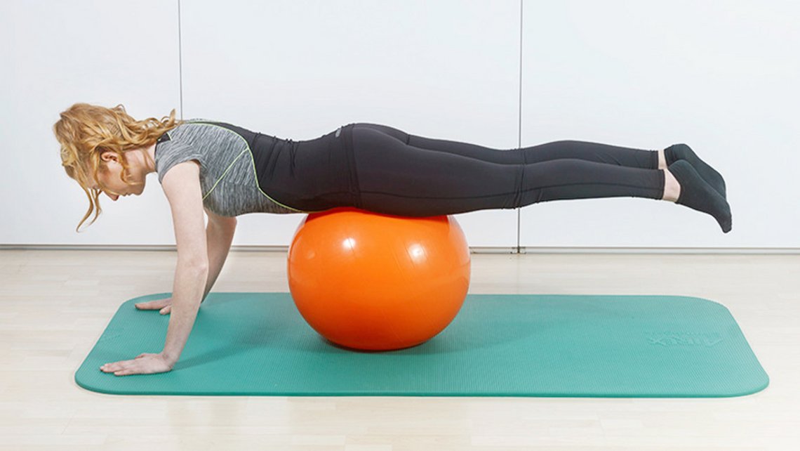 Frau führt Übungen auf einer Matte aus, mit einem Gymnastikball