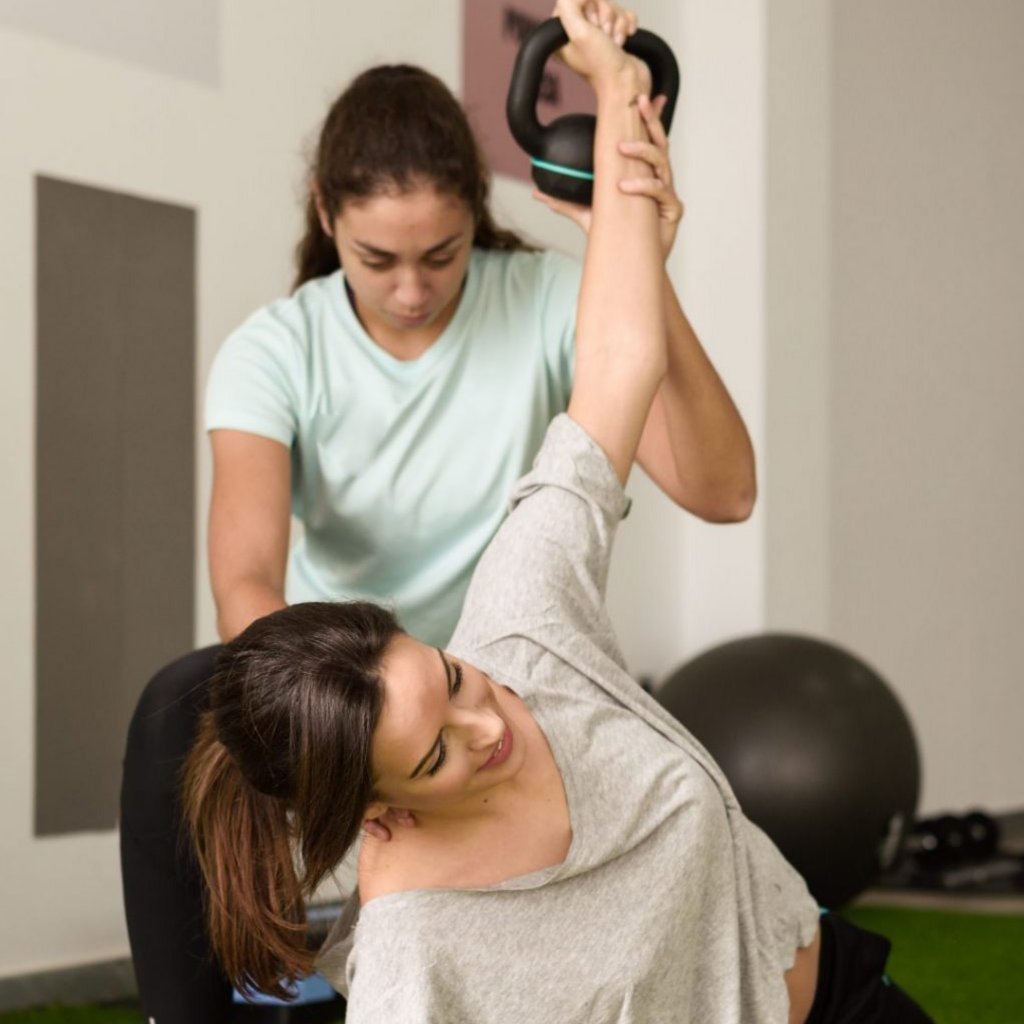 Therapeutin unterstützt Patientin bei einer Gleichgewichtsübung