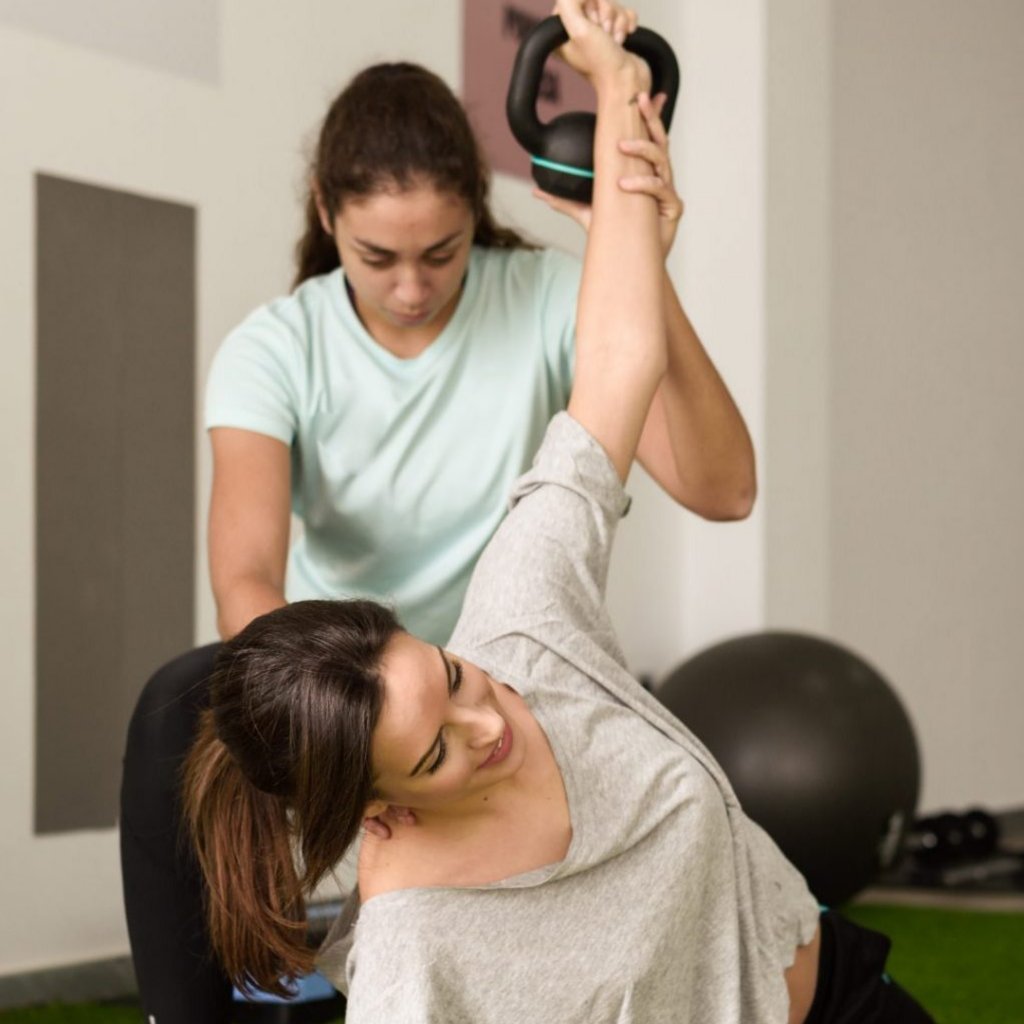 Therapeutin unterstützt Patientin bei einer Gleichgewichtsübung