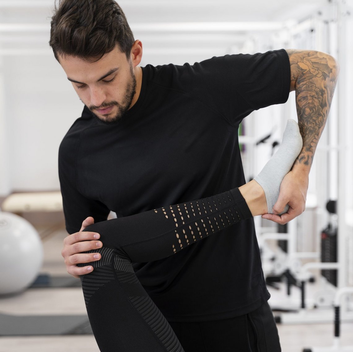 Physiotherapeut zeigt Dehnübung mit Patient im Trainingsraum