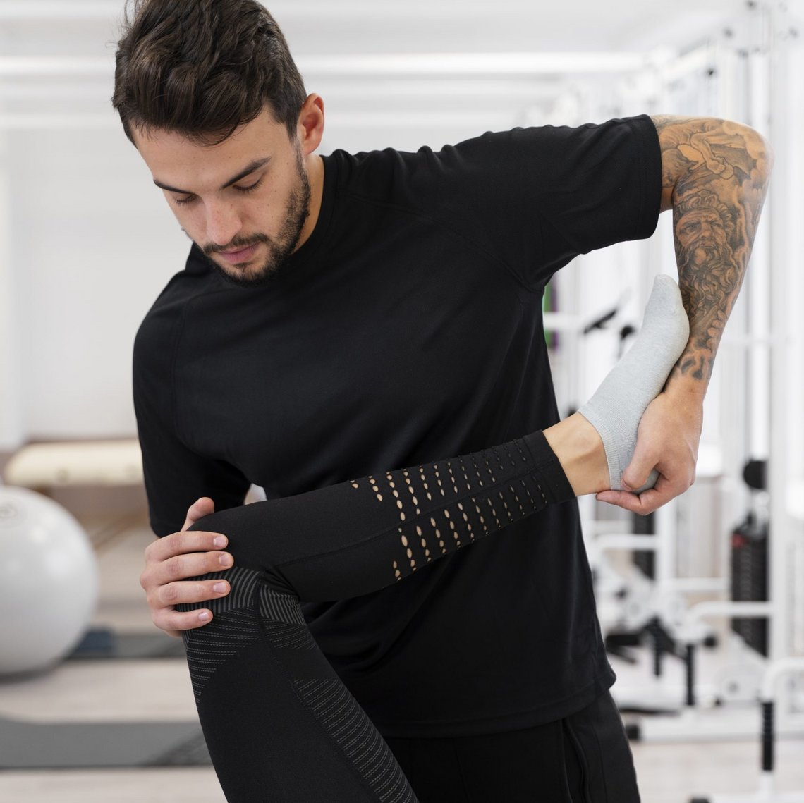 Physiotherapeut zeigt Dehnübung mit Patient im Trainingsraum